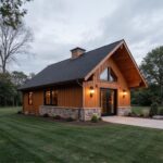 A modern single story barndominium surrounded by greenery, showcasing a unique blend of rustic charm and contemporary design